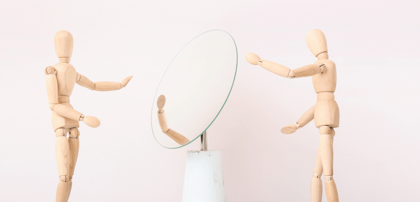 Wooden figures looking in a mirror